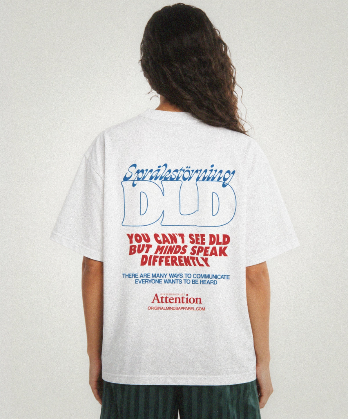 Woman seen from behind in a white T-shirt with the Riksförbundet Attention print "Språkstörning DLD: You can't see DLD but minds speak differently"